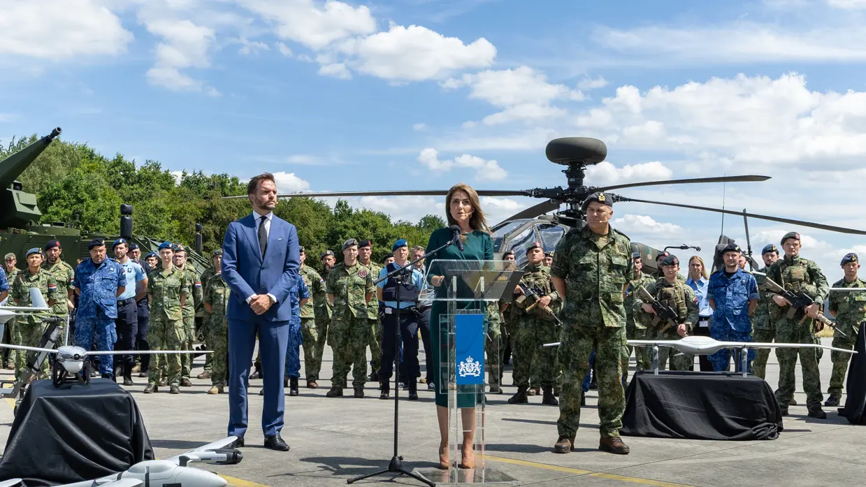 De minister van Defensie geeft een toespraak, met de staatsecretaris en opperbevelhebber van Defensie naast haar. In de achtergrond staan militairen paraat.