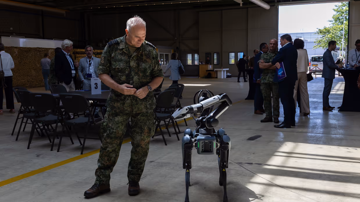 Commandant der Strijdkrachten Eichelsheim kijkt naar een robot. 