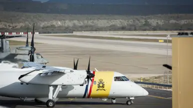 Op de tweede foto de witgele neus van het Dash 8 patrouillevliegtuig met daarachter een neus van een grijs vliegtuig.