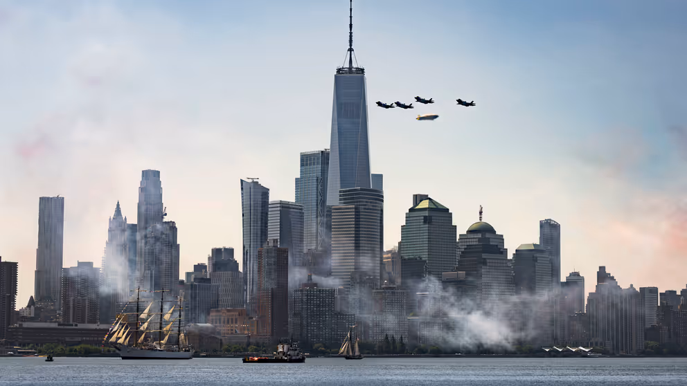 De Amerikaanse stad New York. Ervoor varen schepen en erboven vliegen militaire toestellen.