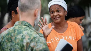 Miriam in oranje shirt in gesprek met een Nederlandse militair. 