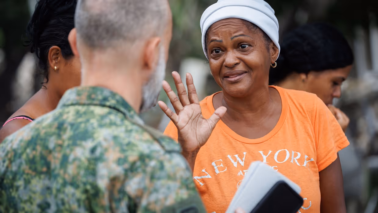 Miriam in oranje shirt in gesprek met een Nederlandse militair. 