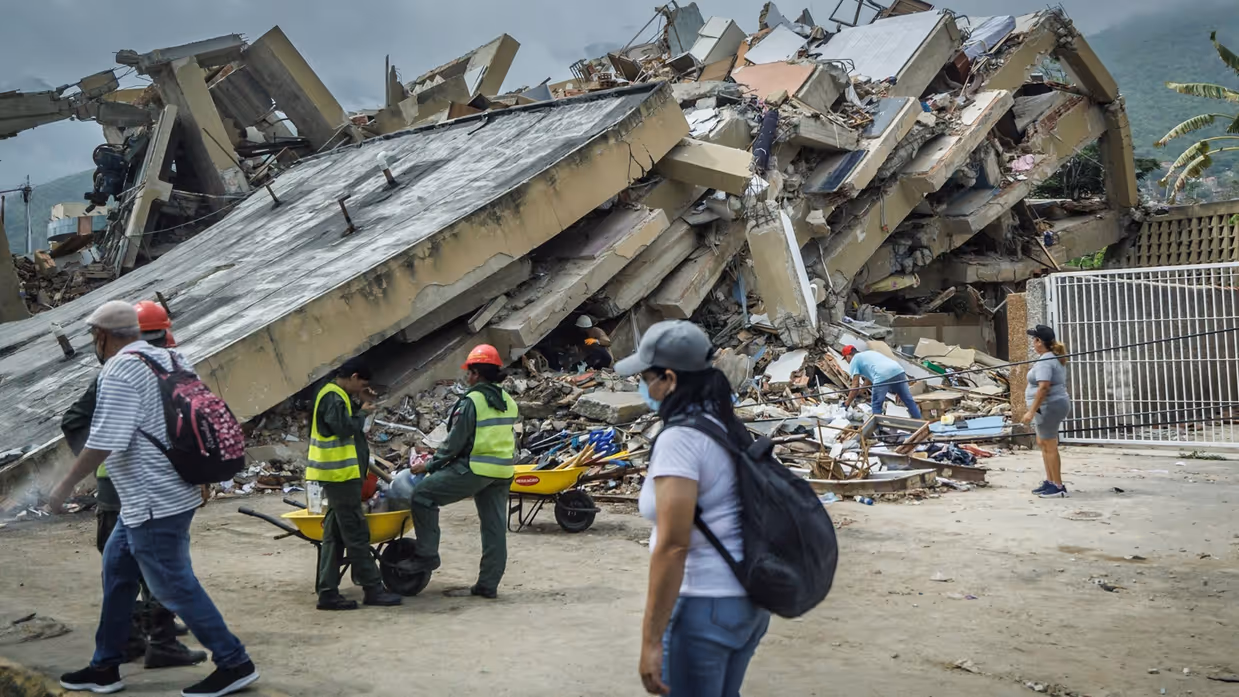 Er lopen mensen langs een volledig ingestort gebouw. 