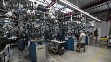 Medewerker bedient controlepaneel van grote machines in productiehal.  