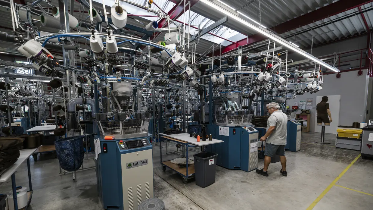 Medewerker bedient controlepaneel van grote machines in productiehal.  