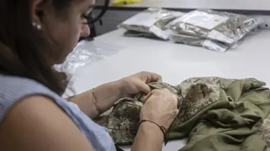 Vrouw controleert binnenzakken militair kledingstuk.