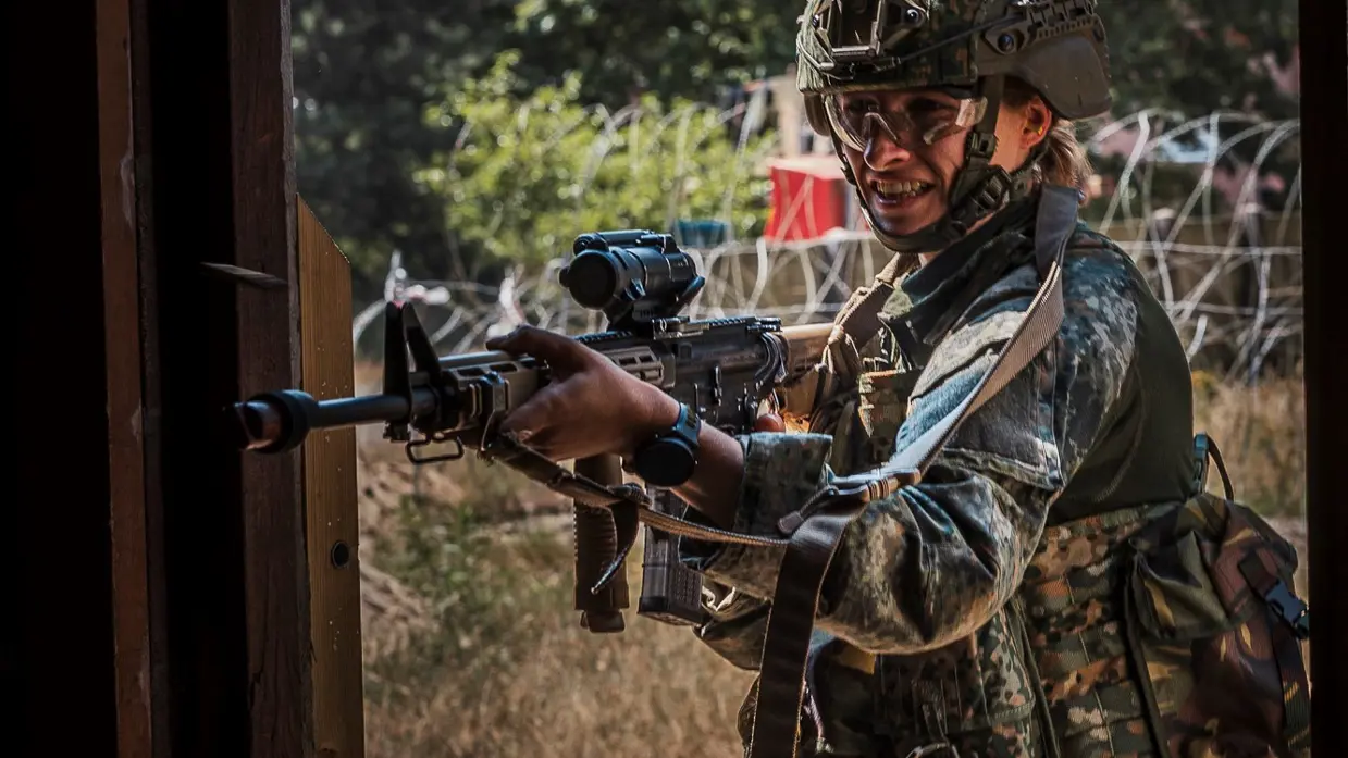 Een studentmilitair staat paraat in een deuropening.