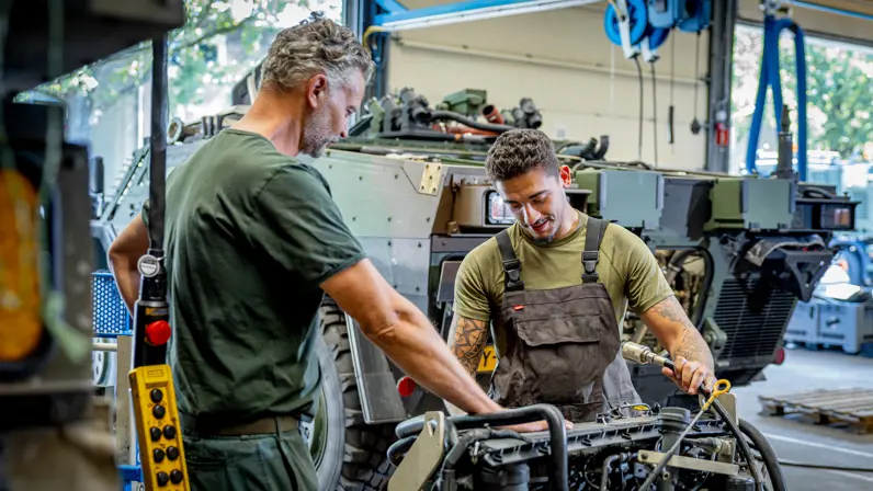 een leermeester die in de werkplaats toekijkt bij een leerling. 