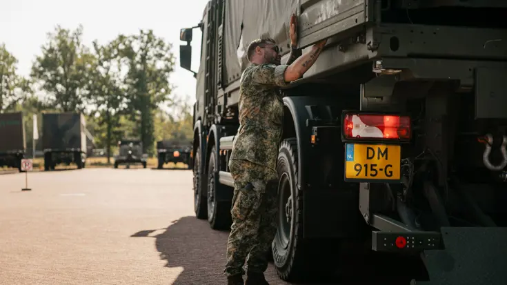 Mike is bezig met de deur van de laadbak van een Scania.