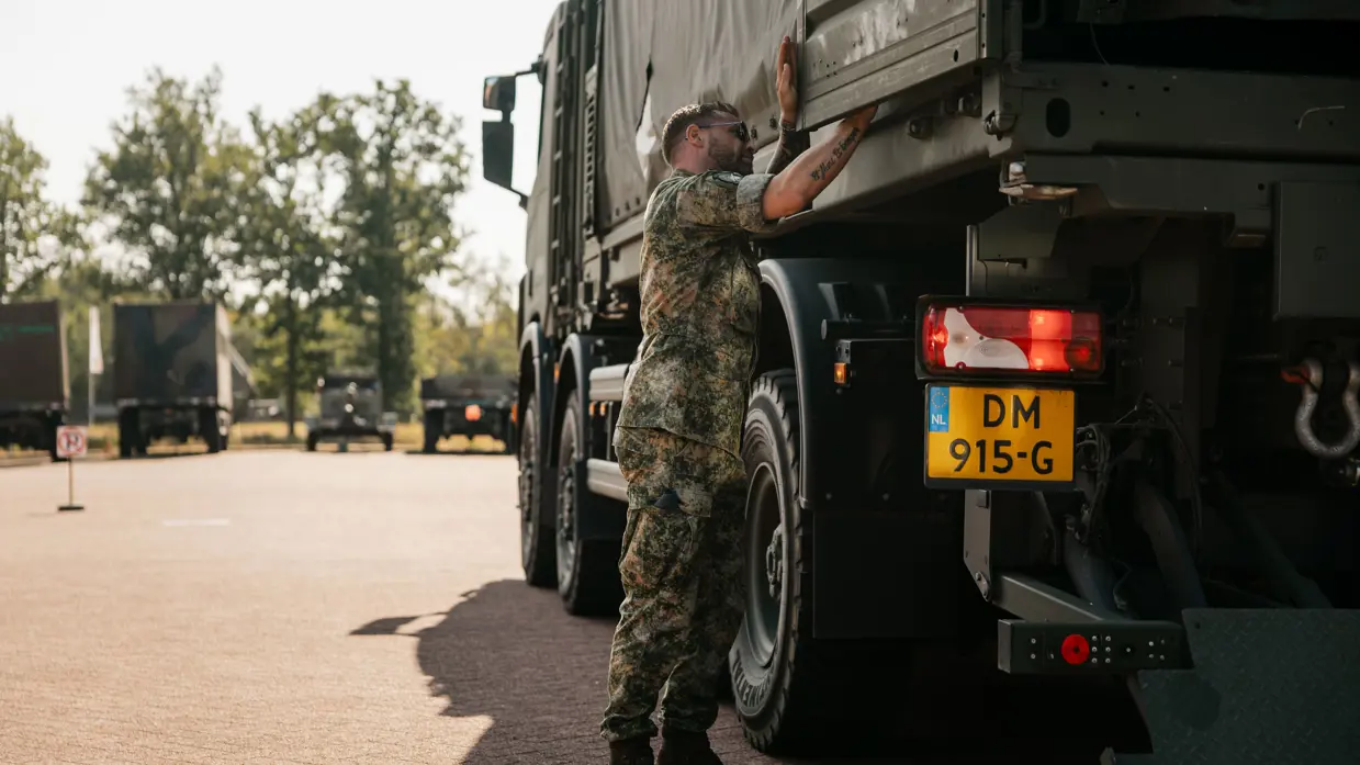 Mike is bezig met de deur van de laadbak van een Scania.