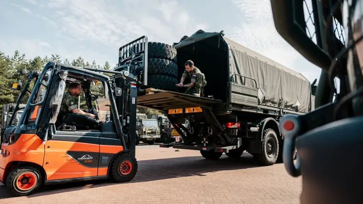 Mike zit in een heftruck en laadt banden in een Scania.