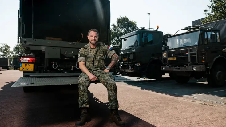 Mike zit op de laadklep van een Scania.