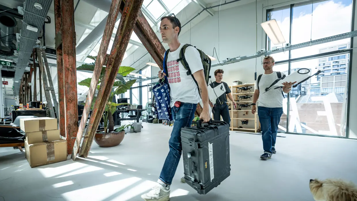 Medewerkers van Intelic bewegen door het pand met koffers en drones.