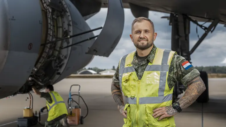 Sergeant-majoor Roy van der Mark draagt een veiligheidsvest en staat naast een A330 MRTT tijdens onderhoudswerkzaamheden. 