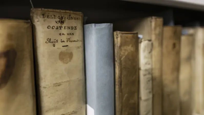 Enkele oude boeken op een rij met verweerde kaften. Op één kaft is te lezen dat dit boem over het beleg van Oostende gaat.