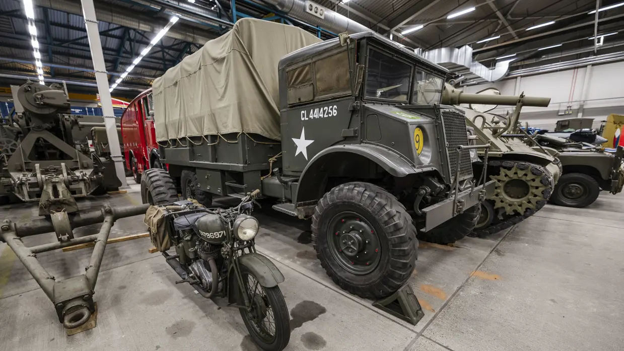 Een motorfiets staat naast een oude legervrachtwagen