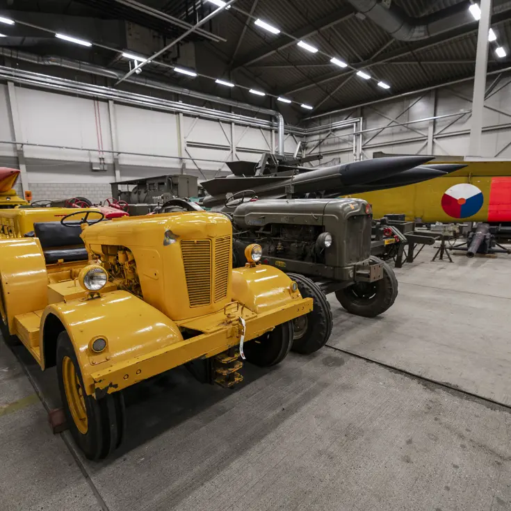 Een knalgeel voertuig staat naast een groene tractor, erachter de raketten van het HAWK-wapensysteem.