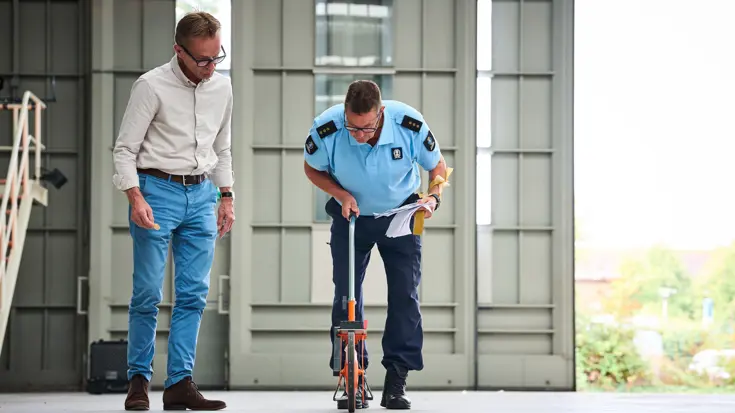 Met een rolmeter meet Dennis de afstand op de vloer van de hal.