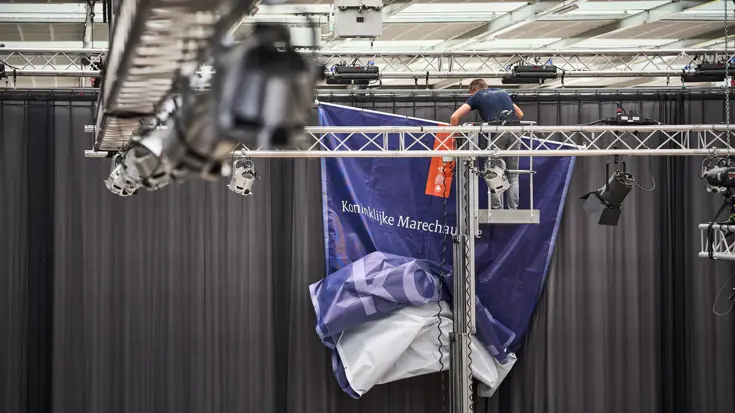 Een doek van de Koninklijke Marechaussee wordt opgehangen.