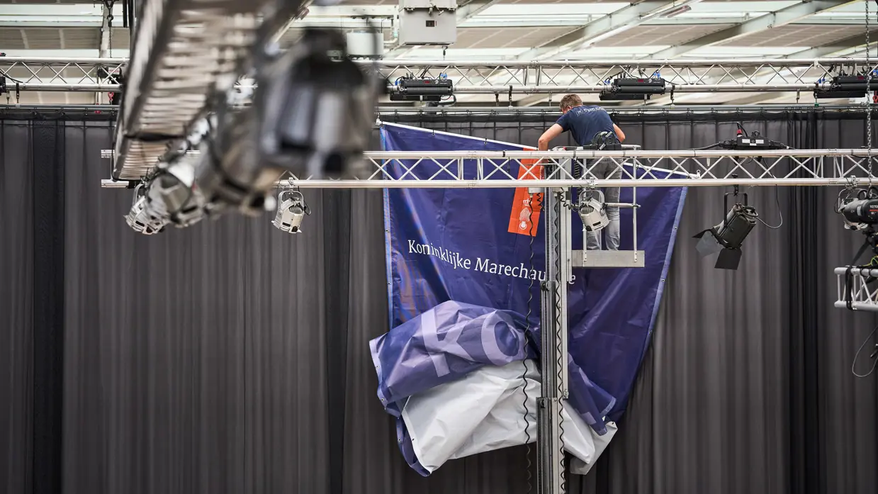 Een doek van de Koninklijke Marechaussee wordt opgehangen.