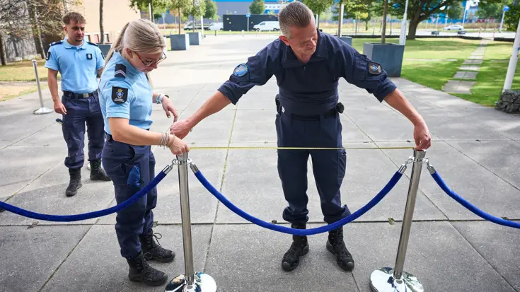 Een marechaussee meet de afstand tussen twee piketpaaltjes.