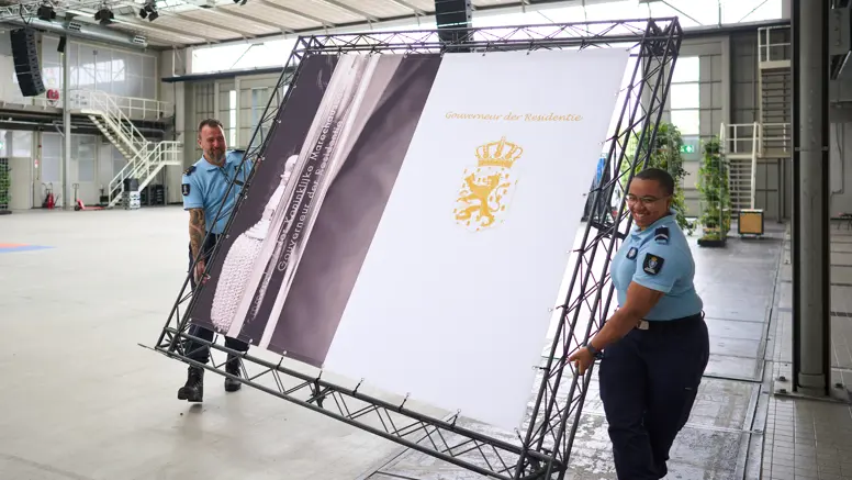 Dennis en een collega dragen een scherm door de hal