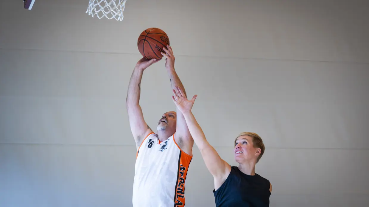 Twee deelnemers duelleren om de bal bij een basket.
