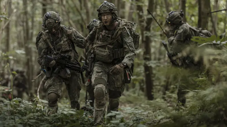  Een groep militairen verplaatst zich door het bos. 