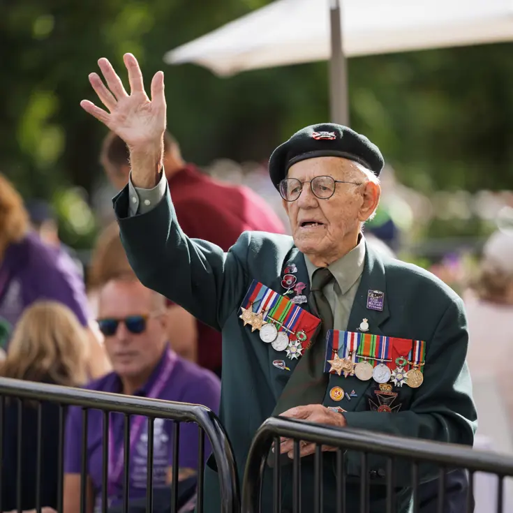 Een oudere veteraan zwaait naar de wandelaars.