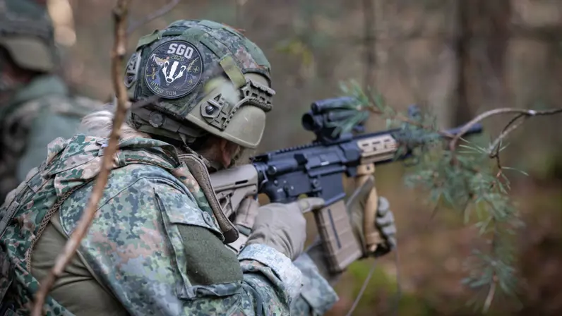 Een militair in schietende houding met op een patch achterop zijn helm waarop staat ‘SGO’.