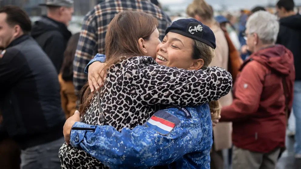 Twee vrouwen omhelzen elkaar op de kade van Den Helder