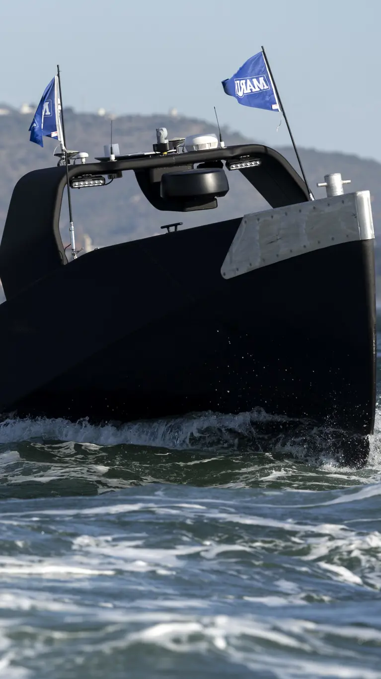 Een zwart, onbemand bootje scheurt over het water.