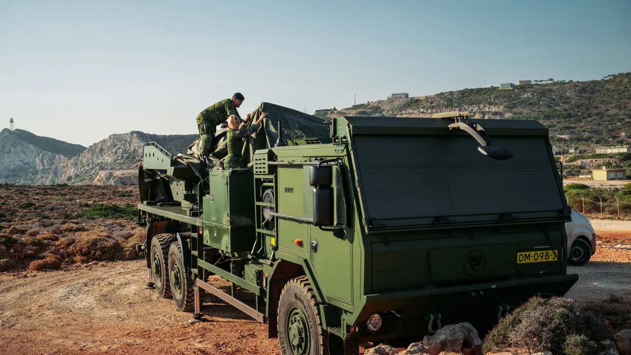 Militairen dekken de lanceerinrichting toe met grote, groene zeildoeken.