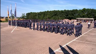 Militairen staan opgesteld op een paradeplaats.