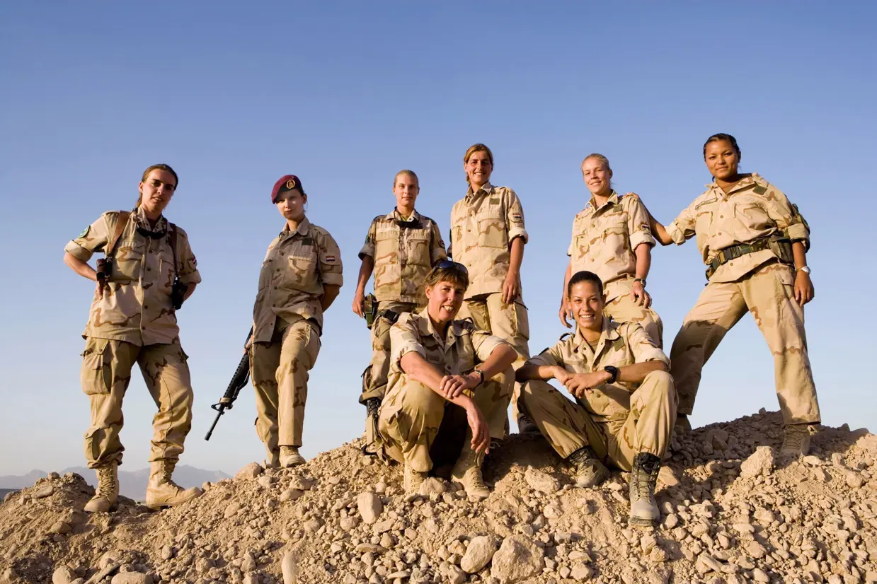 Vrouwelijke militairen poseren in Afghaans landschap.