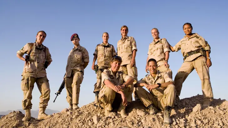 Vrouwelijke militairen poseren in Afghaans landschap.