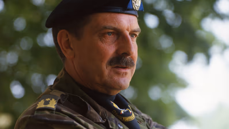 Een militair met snor en zwarte baret in uniform.