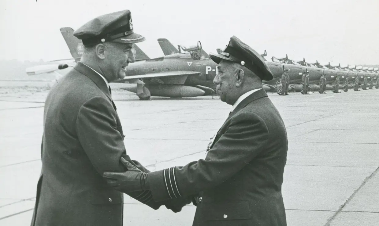 Zwart-wit foto van 2 militairen die elkaar een hand geven.