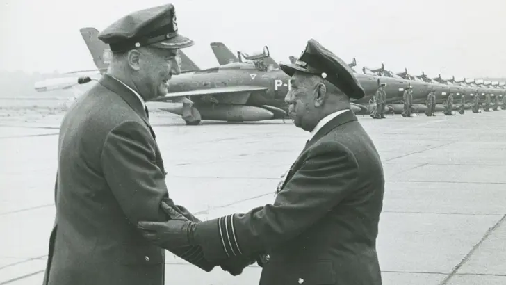 Zwart-wit foto van 2 militairen die elkaar een hand geven.