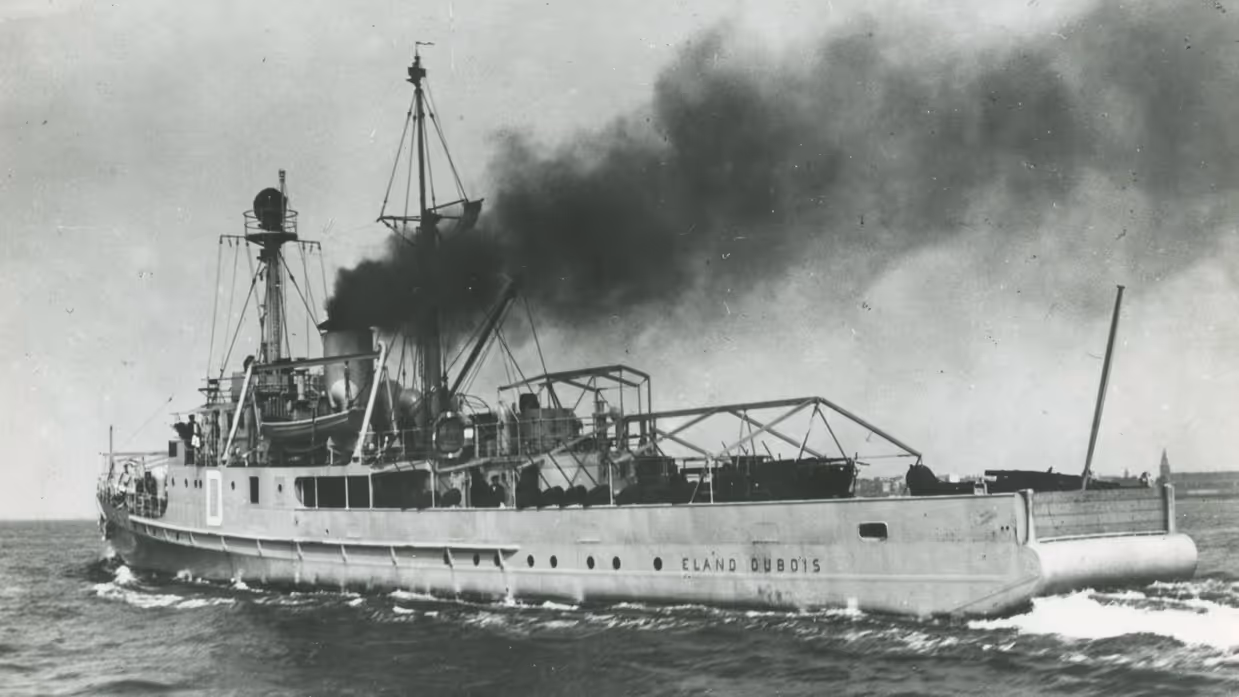  Een groot, oud schip genaamd Eland Dubois vaart op zee. Uit de schoorsteen komt dikke, zwarte rook en het schip heeft masten en een open dek.