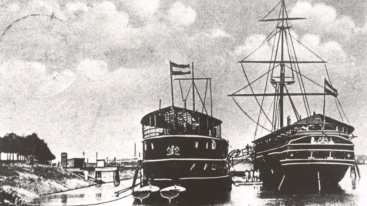 2 historische schepen, een stoomschip en een zeilschip, afgemeerd in een haven bij Gorinchem, met vlaggen en mensen aan boord.