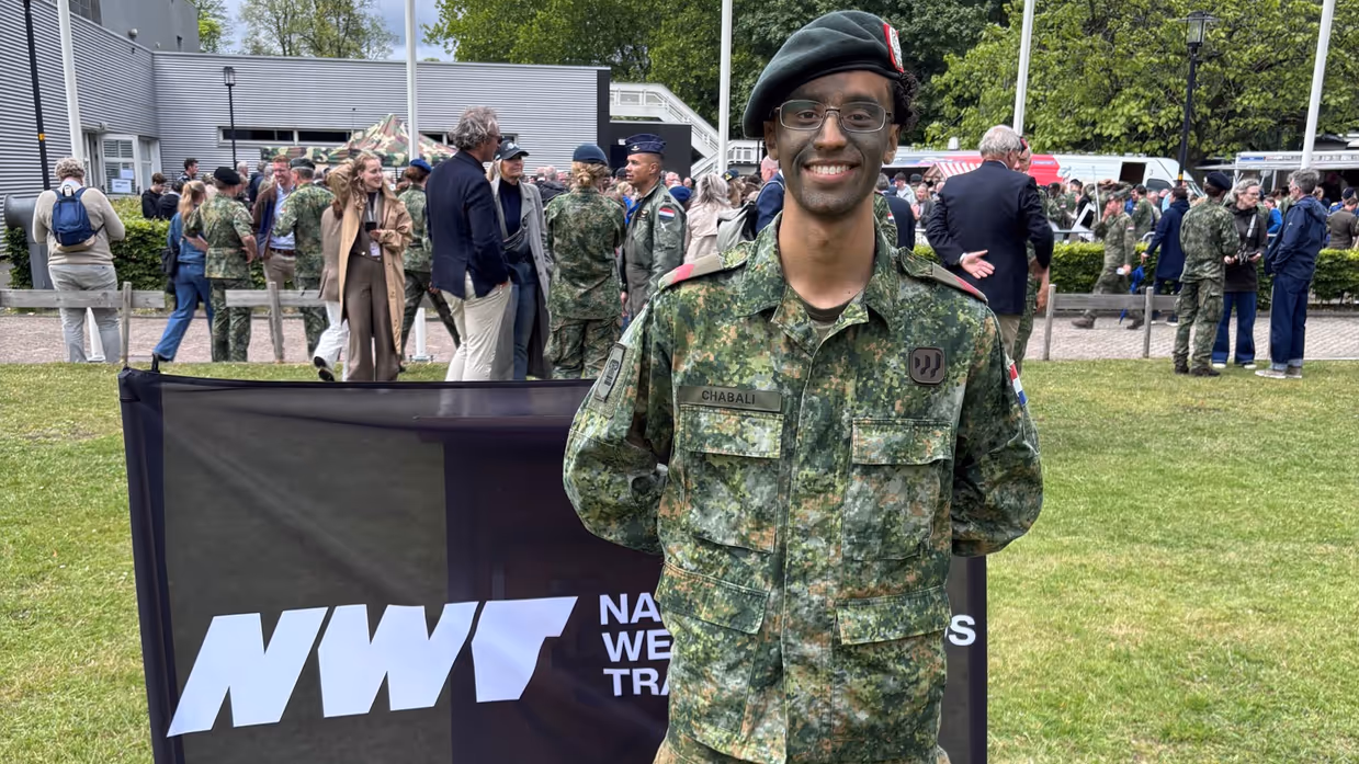 Een militair staat op een grasveld. 