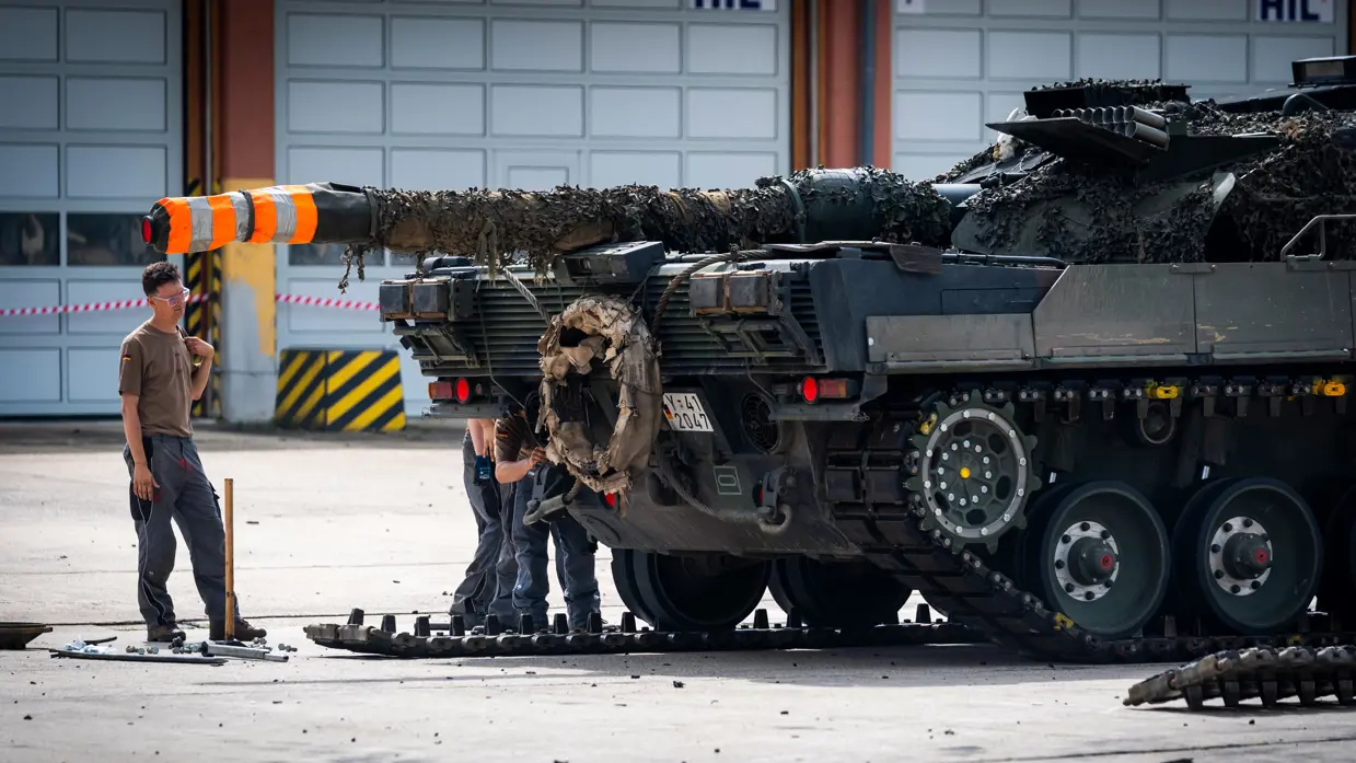 Twee huzaren staan onder het kanon van de Leopard op een grote parkeerplaats.