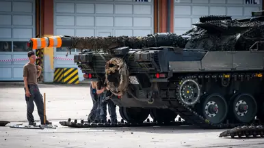 Twee huzaren staan onder het kanon van de Leopard op een grote parkeerplaats.