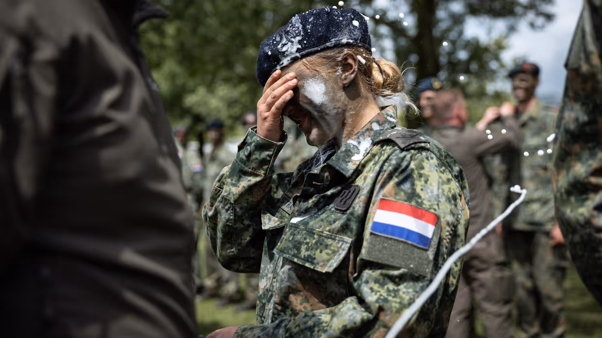 Een vrouwelijke militair met bier op haar schouders, gezicht en baret.