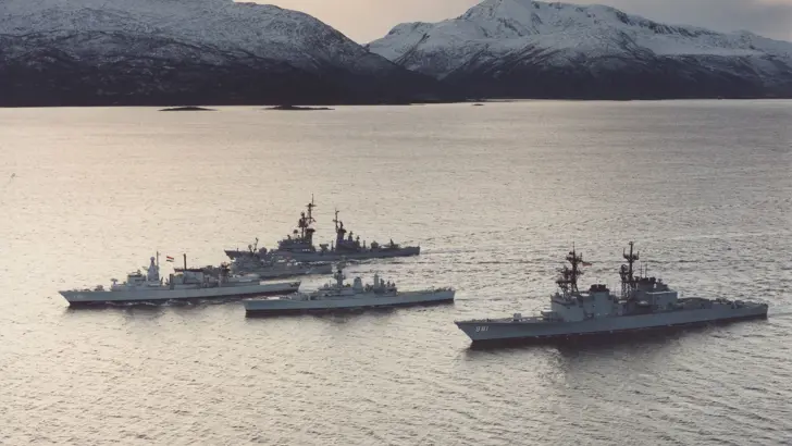 Foto uit 1986. Fregat Hr. Ms. Witte de With als eenheid van de Stanavforlant (Standing Naval Force Atlantic) op zee voor besneeuwde bergen.