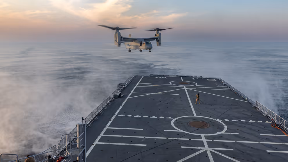 Een vliegtuig hangt boven een scheepsdek.