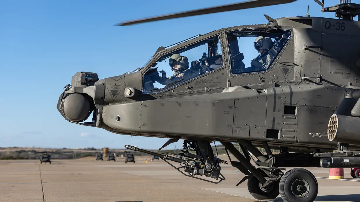 Twee vliegers in de cockpit van een Apache op een platform.