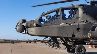 Twee vliegers in de cockpit van een Apache op een platform.