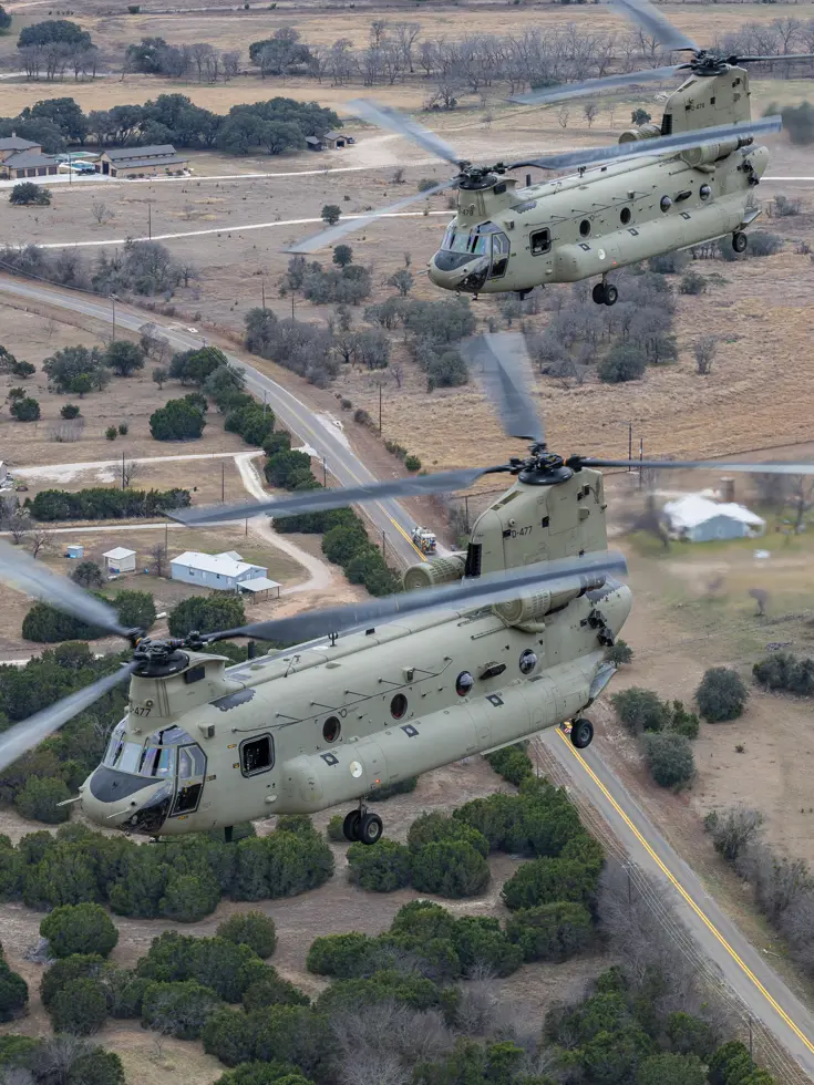 Twee Chinooks van bovenaf vliegend over Texaans landschap.
